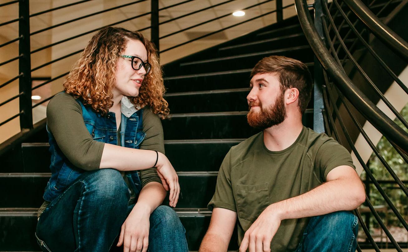 Photo of two students sitting and talking on stairs