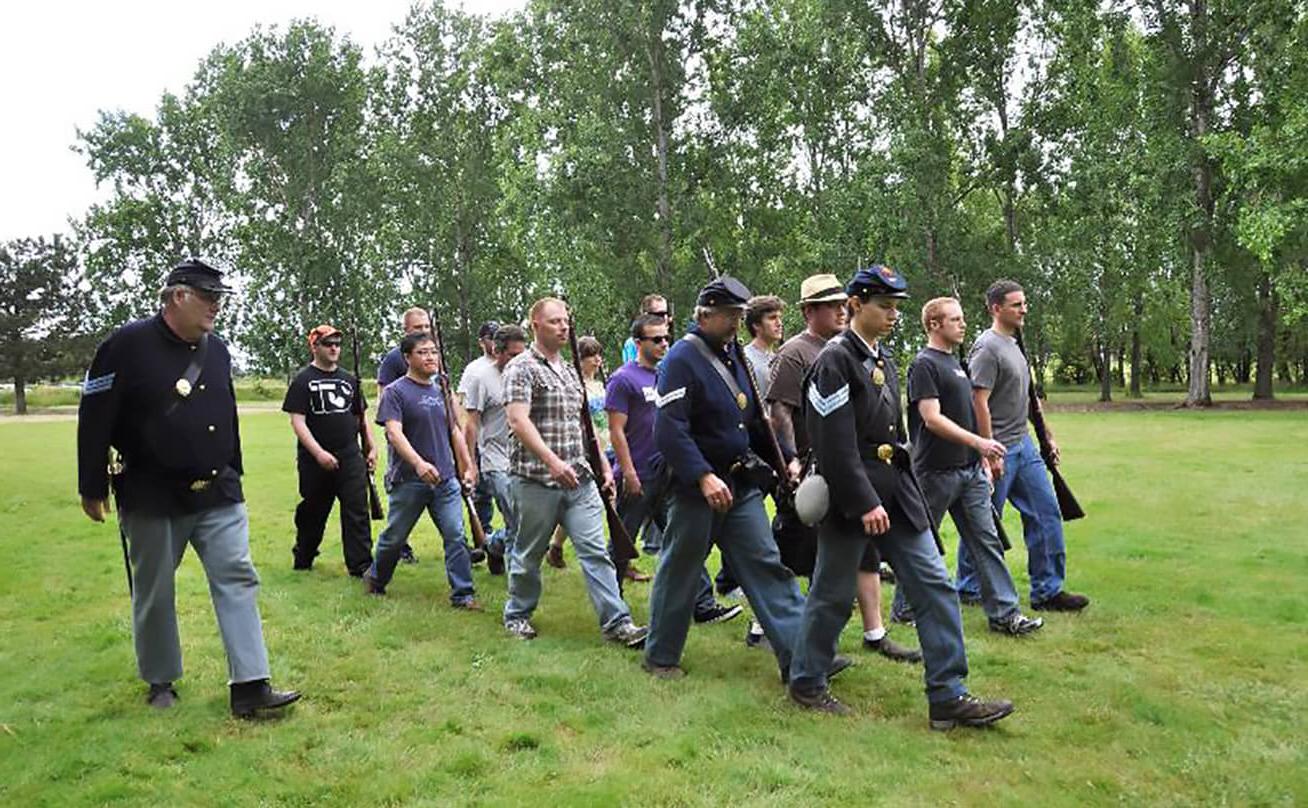 Students marching in Civil War reenactment with professor in uniform