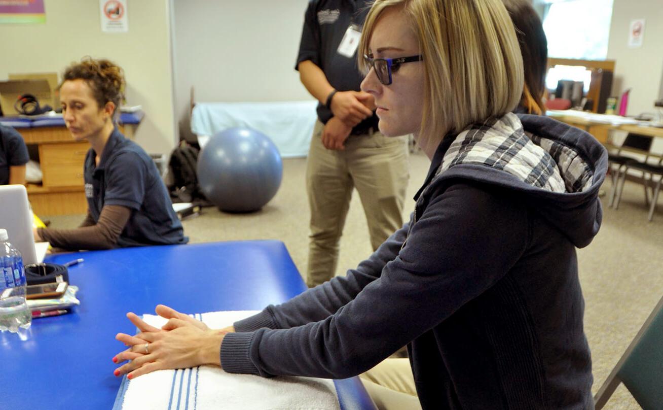 Occupational therapy classroom with female student holding hands on towel on table