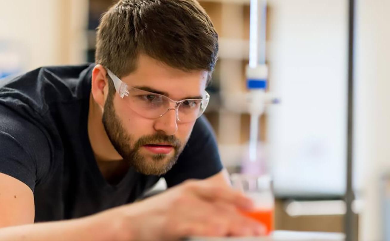 Male student using lab equipment in class